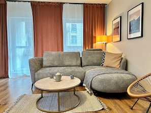 Una sala de estar acogedora con un sofá gris, una mesa redonda de centro y una silla de mimbre.