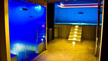 Un hall d’hôtel avec un ascenseur éclairé de lumière bleue, un escalier et un comptoir d’accueil.