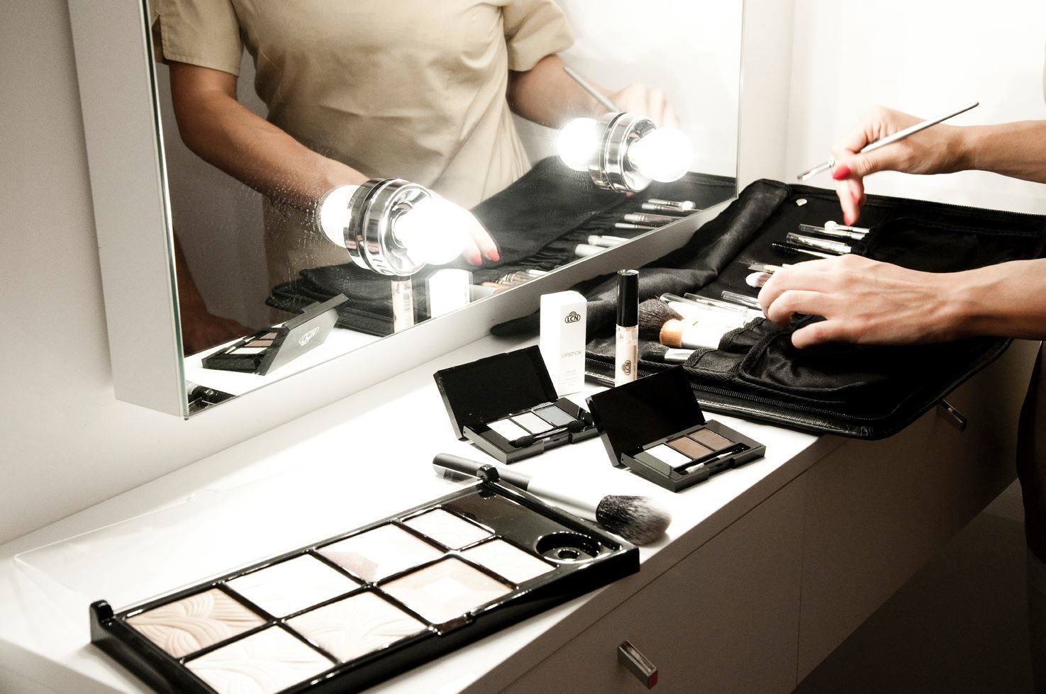 Una postazione per il trucco con specchio, luci e diversi prodotti di make-up.