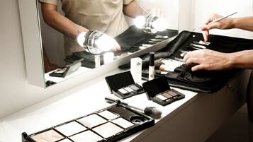Una postazione per il trucco con specchio, luci e diversi prodotti di make-up.