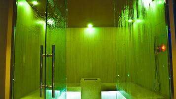 A glass-enclosed shower area with a tiled floor, a glass door, and a metal handle.