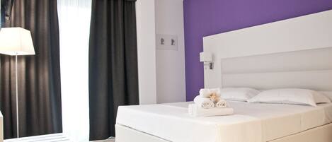 Una habitación de hotel moderna con una cama grande, una lámpara de noche y vistas al exterior.