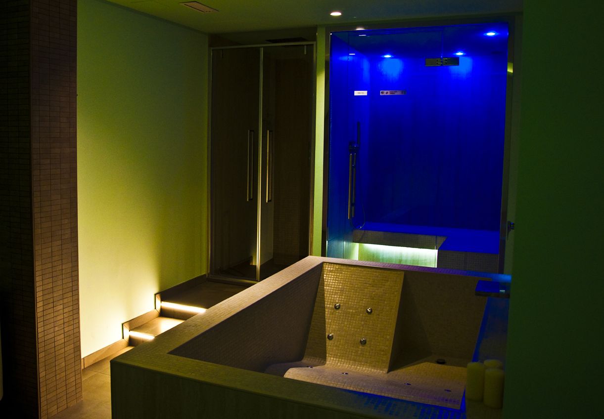 A modern bathroom with a large bathtub, a shower area, and a glass-enclosed sauna.