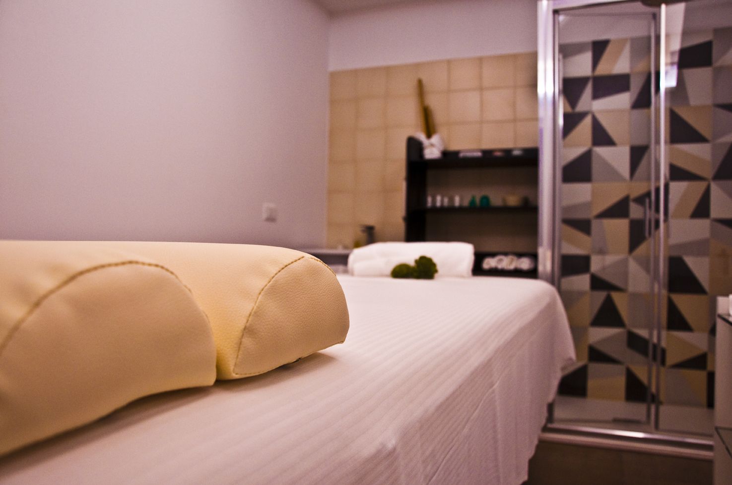 A hotel room with a bed, a shower area, and a bathroom with a geometric tile backsplash.