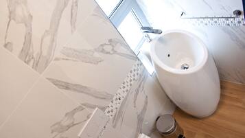 Une salle de bain moderne avec des carreaux de marbre, un bidet et un plancher en bois.