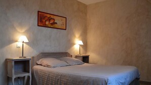 Een slaapkamer met een bed, twee nachtkastjes en een schilderij aan de muur.