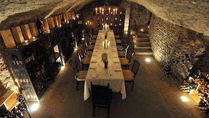 An underground dining area with a long table set for a meal, surrounded by wine racks and stone walls. - Villa Mangiacane (San Casciano)