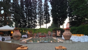 An outdoor garden setting with a central pool, surrounded by seating areas and potted plants. - Villa Mangiacane (San Casciano)