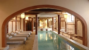A pool area with a long, narrow pool, a seating area with cushioned chairs, and a dining area with tables and chairs. - Villa Mangiacane (San Casciano)