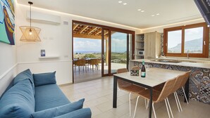 Una cocina moderna con un gran ventanal, un comedor con mesa y sillas, y un sofá azul.