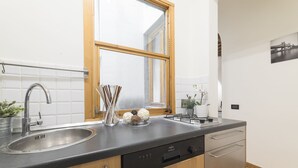 Een moderne keuken met een roestvrijstalen spoelbak, een vaatwasser, houten kastjes en een raam met uitzicht op een brug.