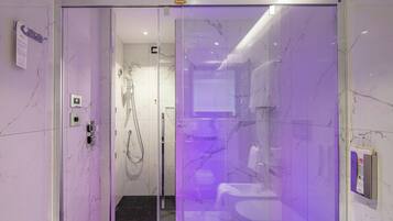A modern bathroom with a glass shower enclosure, marble walls, and a visible control panel.