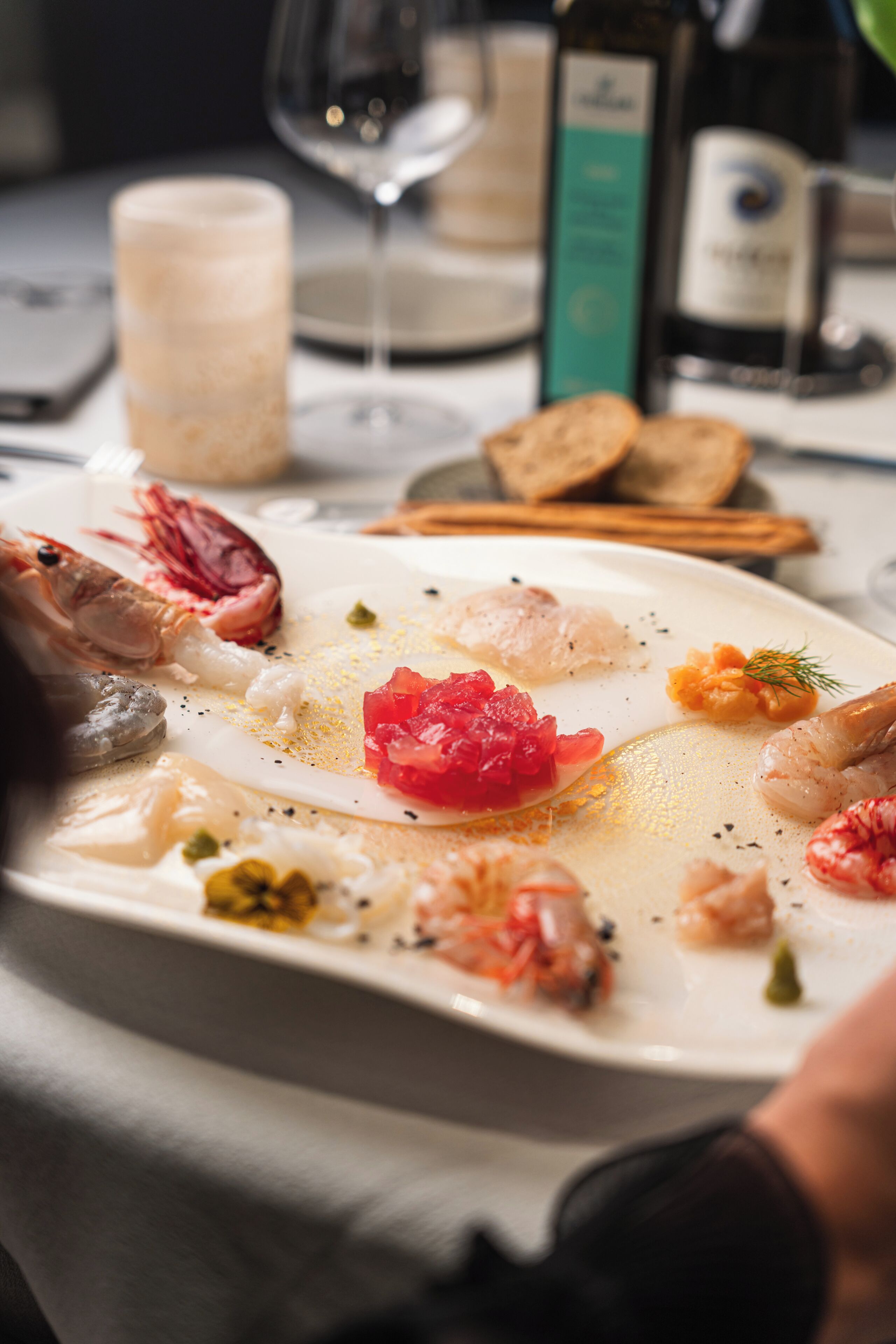 Una mesa de comedor con mariscos, vino y una vela.