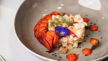 A plate with lobster, cream, and garnishes on a table.