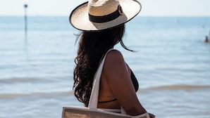 A person with a straw hat and a tote bag with 'Monaco Suites Hotel' text. - Monaco Suites Hotel (Lignano Sabbiadoro)