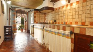 A kitchen with tiled walls, a wooden ceiling, and a tiled floor. - Villa Del Poggio (Castellammare del Golfo)