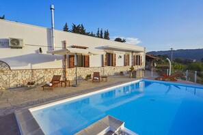 A swimming pool with lounge chairs and a stone wall. - Villa Del Poggio (Castellammare del Golfo)