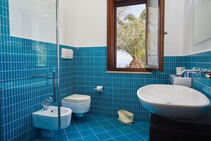 A bathroom with blue tiles, a white sink, a toilet, and a bidet.