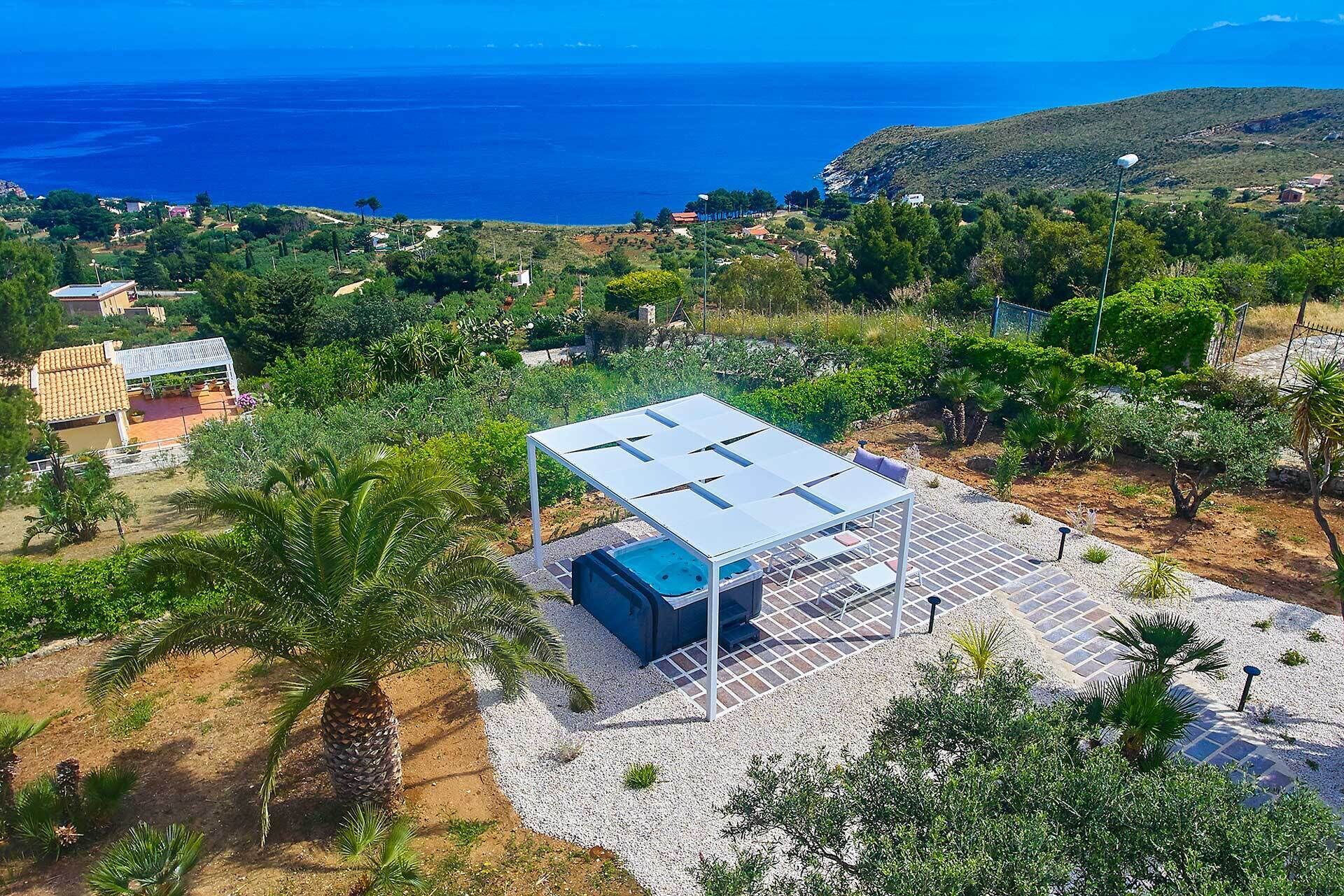Une villa moderne dotée d’une terrasse sur le toit, entourée d’une végétation luxuriante et offrant une vue sur la mer.