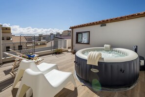 A rooftop terrace with a hot tub, white plastic chairs, and a view of neighboring buildings. - La Suite Di Tyche (Castellammare del Golfo)