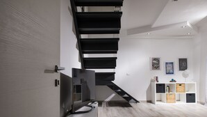 A modern interior with a staircase, a white console table, and framed artwork on the wall. - La Suite Di Tyche (Castellammare del Golfo)