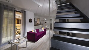 A modern living room with a purple sofa, a small table with a chessboard, and a staircase with metal railings. - La Suite Di Tyche (Castellammare del Golfo)