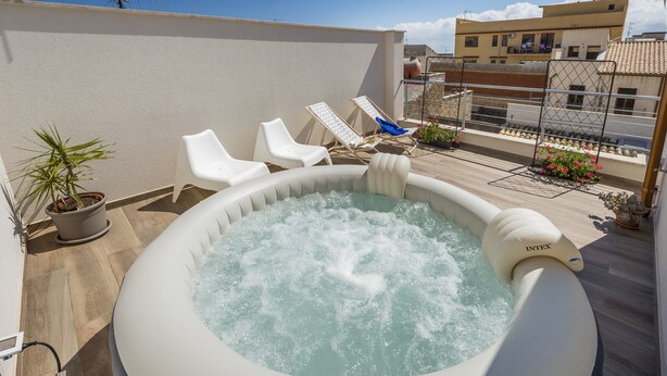 An inflatable hot tub with two white lounge chairs and a potted plant on a rooftop terrace. - La Suite Di Tyche (Castellammare del Golfo)