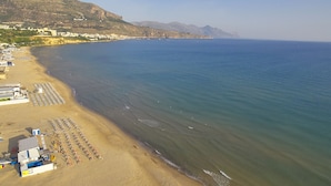 A beach with rows of sun loungers and a building with a flat roof. - Skrokkia (Alcamo)