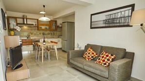 A compact living space with a kitchenette, a dining area, and a sofa with patterned cushions. - Skrokkia (Alcamo)