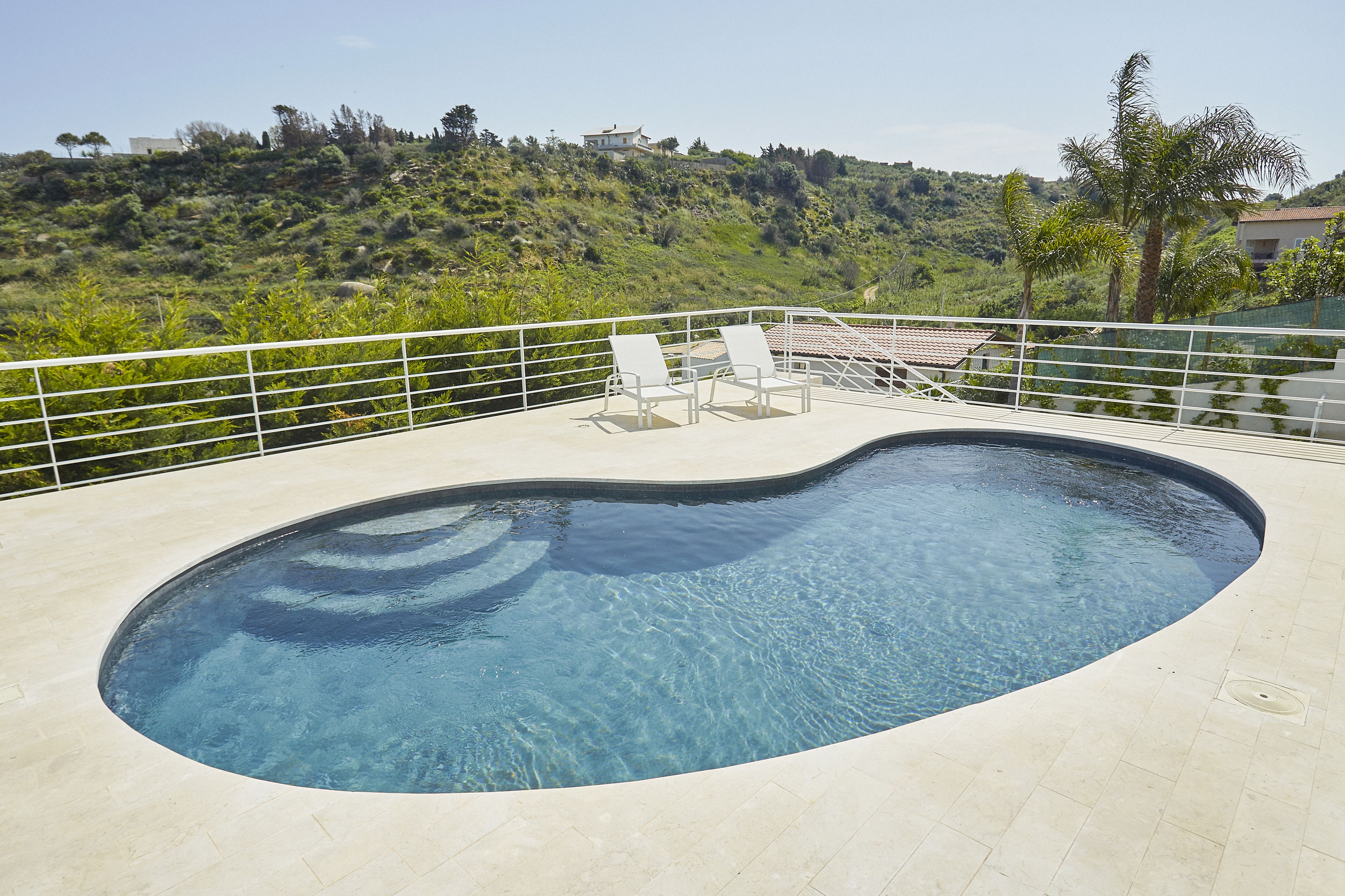 Une piscine avec deux chaises longues et une vue sur une colline.