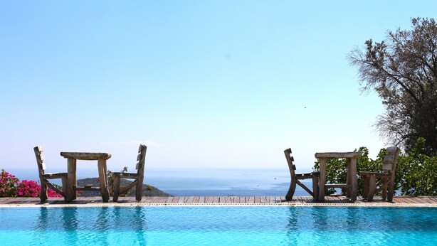 A pool with wooden chairs and a view of the ocean. - Zephyros Hotel (Datça)