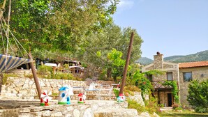 A stone staircase leading to a terrace with outdoor seating and windmills. - Zephyros Hotel (Datça)
