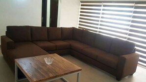 A brown sectional sofa with a wooden coffee table in front. - Gemini Place Apartments (Lagos)
