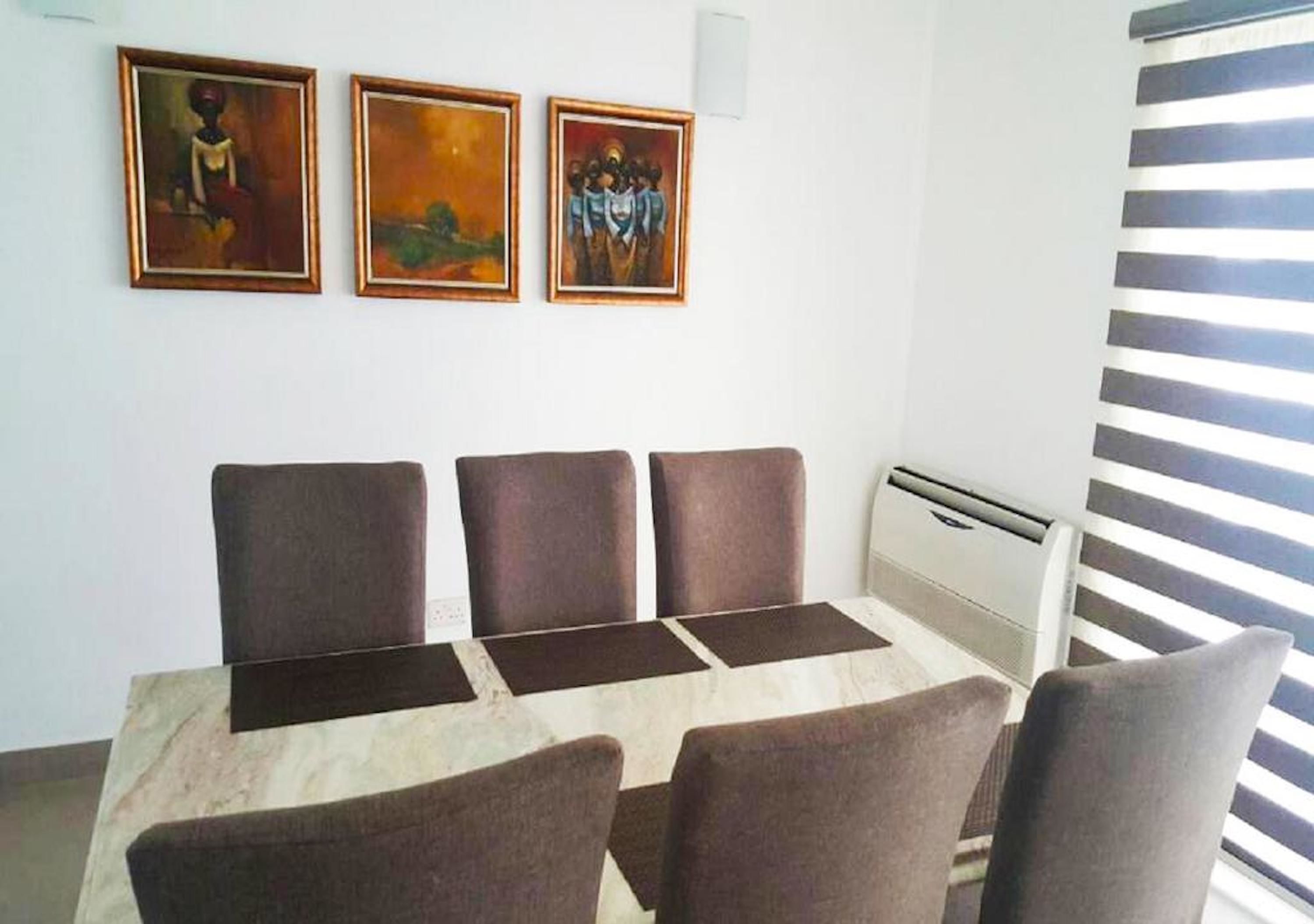 Une salle de conférence avec une table en marbre et quatre chaises. Trois tableaux encadrés sont accrochés au mur.