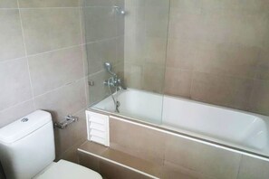 Un baño con ducha de vidrio, inodoro y lavamanos.