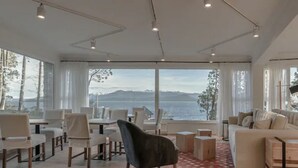 Amplia sala de estar con un gran ventanal con vistas panorámicas, amoblada con un sofá, sillas y una mesita de centro.