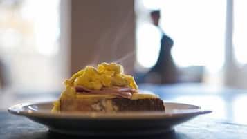 A slice of toast with scrambled eggs and ham on a plate.