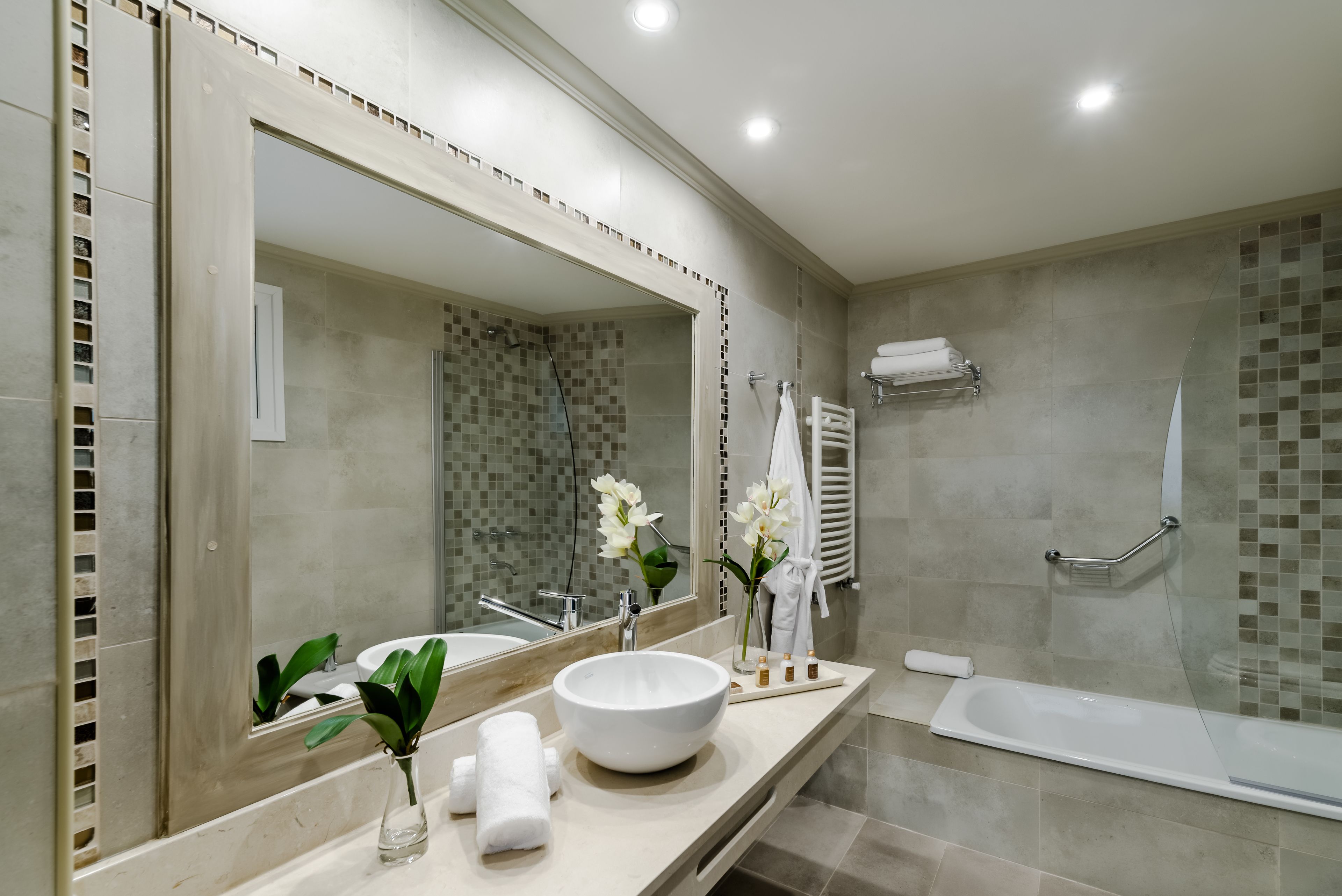 A modern bathroom with a large mirror, a round sink, a bathtub, and a shower area.