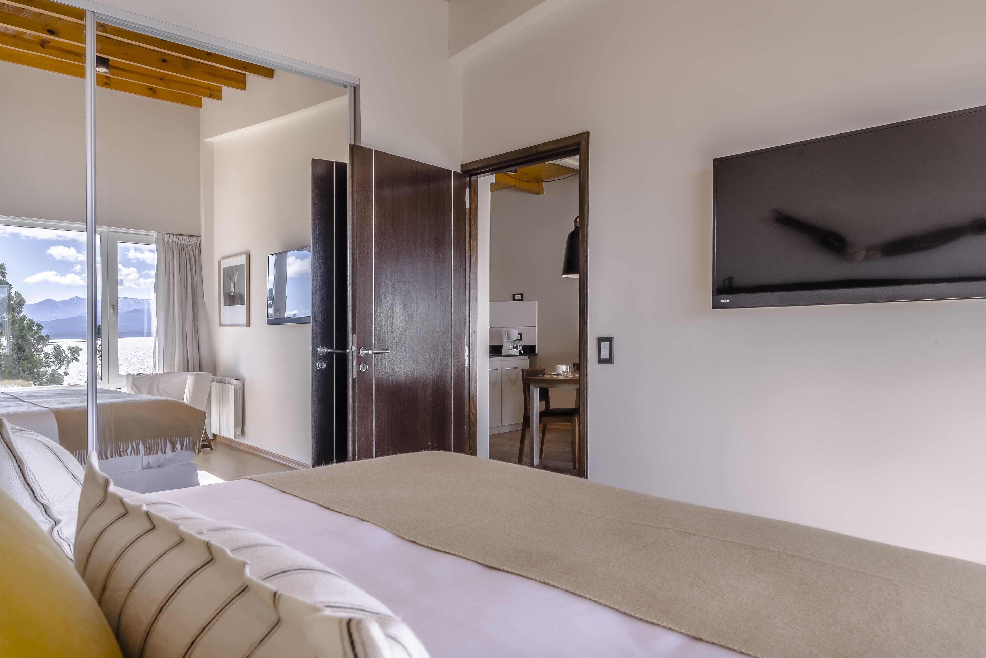 Moderni hotellihuone, jossa on sänky, työpöytä ja näkymä vuorille.