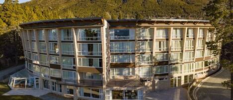 Un hôtel à plusieurs étages, doté d’une façade incurvée, de grandes fenêtres et d’une cour aménagée.