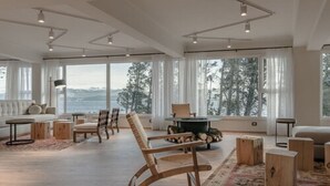 Amplia sala de estar con un ventanal que ofrece vistas al exterior, un rincón de descanso acogedor con sofá y sillones, y una chimenea.