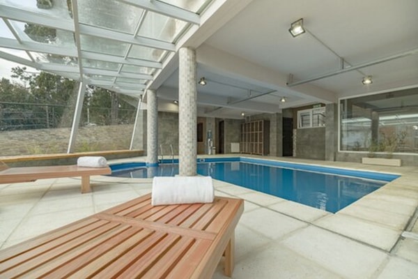 Een binnenzwembad, ligstoelen bij het zwembad