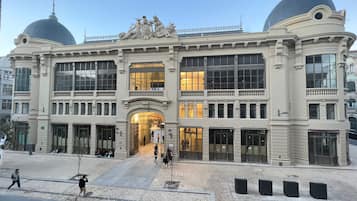 En stor, historisk byggnad med två framträdande kupoler, en central entré och en symmetrisk fasad med stora fönster.