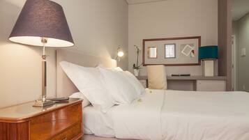 A neatly made bed with white linens, a bedside lamp, and a wooden nightstand with a drawer.
