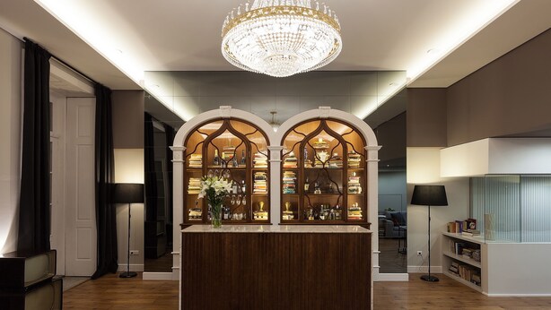 A modern interior with a central wooden display case, a large chandelier, and a mirrored wall. - B The Guest Downtown (Porto)