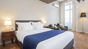 A neatly arranged bedroom with a large bed, bedside tables with lamps, a chair, and a floor lamp. - B The Guest Downtown (Porto)