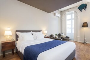 Quarto bem arrumado com uma cama grande, mesas de cabeceira com luminárias, uma cadeira e um abajur.