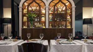 A restaurant with tables set for dining, a bar area with a bookshelf, and a decorative archway. - B The Guest Downtown (Porto)