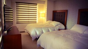A hotel room with two beds, a wooden headboard, a TV, and a window with blinds. - HB Sopocachi (La Paz)