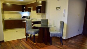 A compact kitchen with dark wooden cabinets, a microwave, and a small dining table with two chairs. - HB Sopocachi (La Paz)
